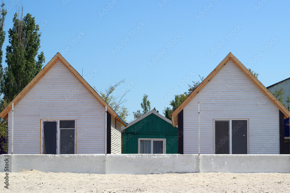 Two identical white houses with one window on the beach Two identical white houses with one window on the beach