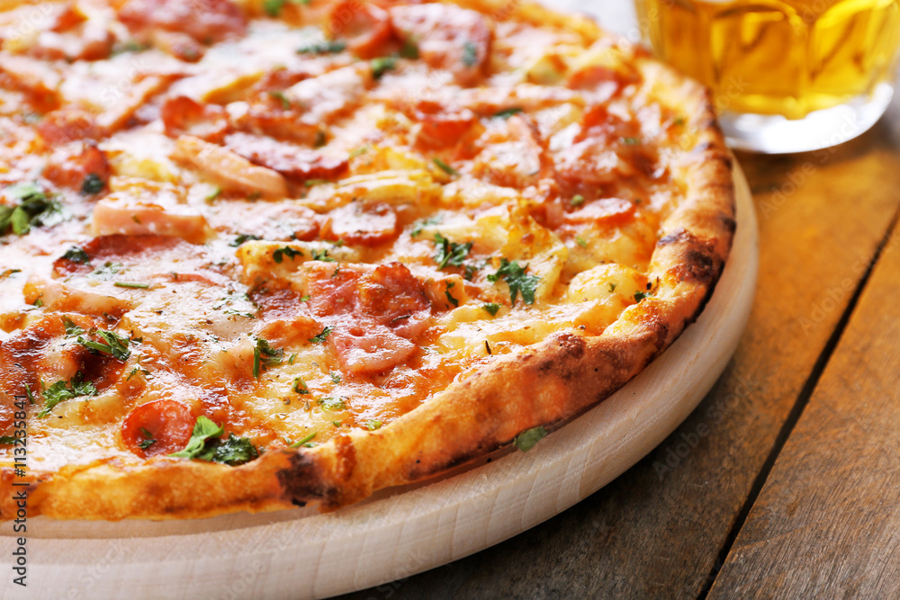 Tasty pizza and glass of beer are on wooden table, close up