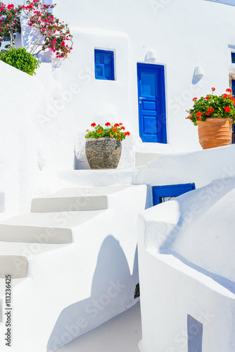 Traditional cycladic whitewashed architecture with blue doors and flower pots, Imerovigli, Santorini island, Greece