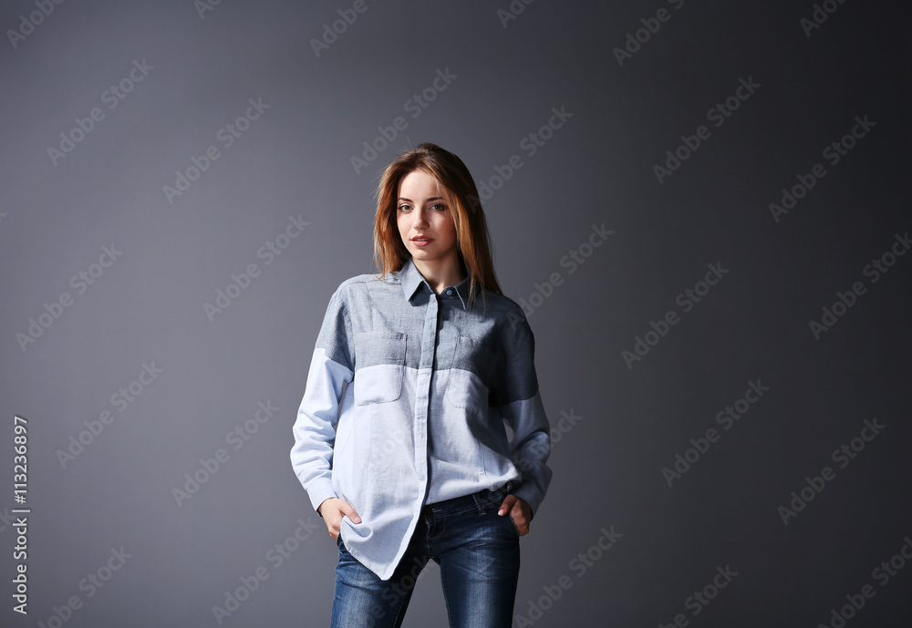 Beautiful young woman in shirt and jeans on grey wall background Beautiful young woman in shirt and jeans on grey wall background
