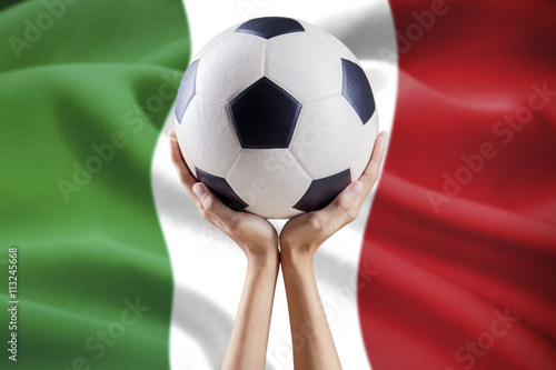Hands hold ball with flag background of Italy
