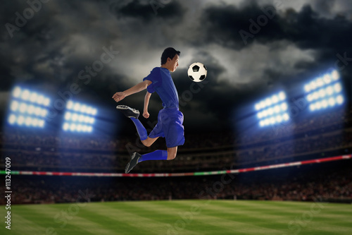 Soccer player playing a ball at night