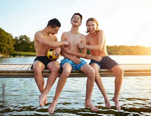 Two teenage friends tickling their mate