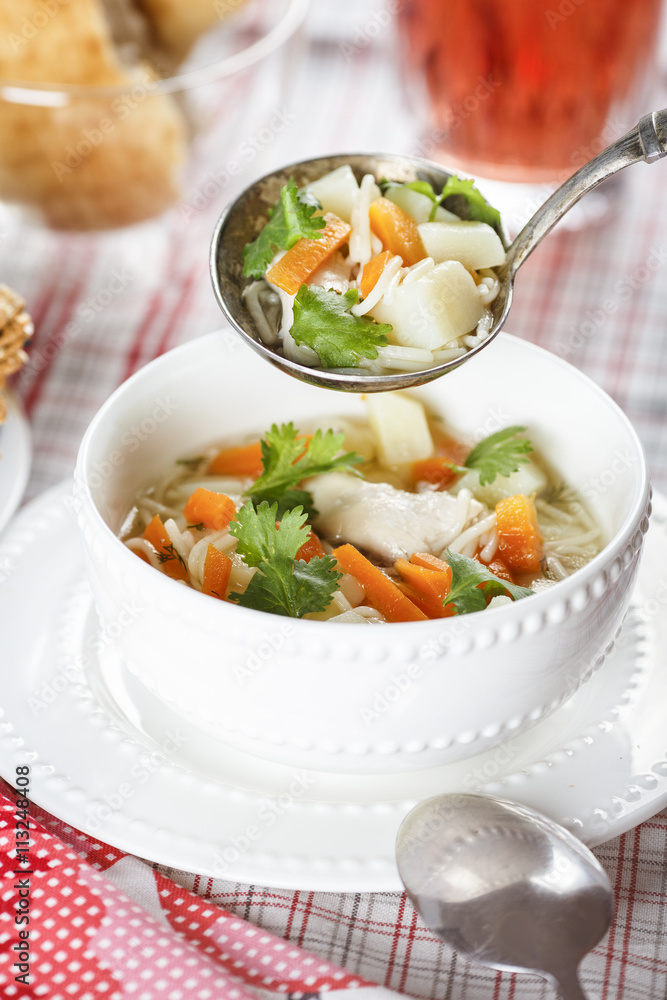 Submission chicken soup with noodles, potatoes and carrot in a white chalice on a tablecloth into a cell Submission chicken soup with noodles, potatoes and carrot in a white chalice on a tablecloth into a cell