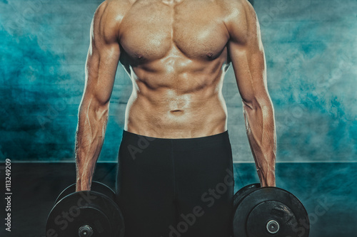 Obraz na plátně Close up of half naked man with dumbbells