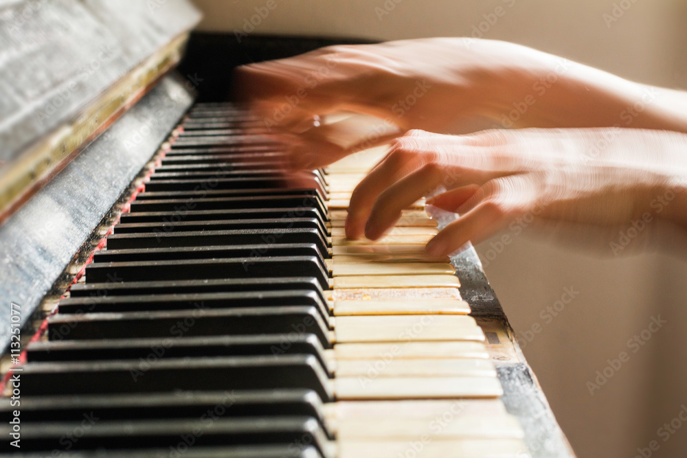 Old rusty piano, selective focus, woman's hands on keyboard, intentionally blurred motion
