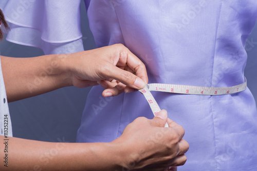 Hand of women taking measurement of coat.