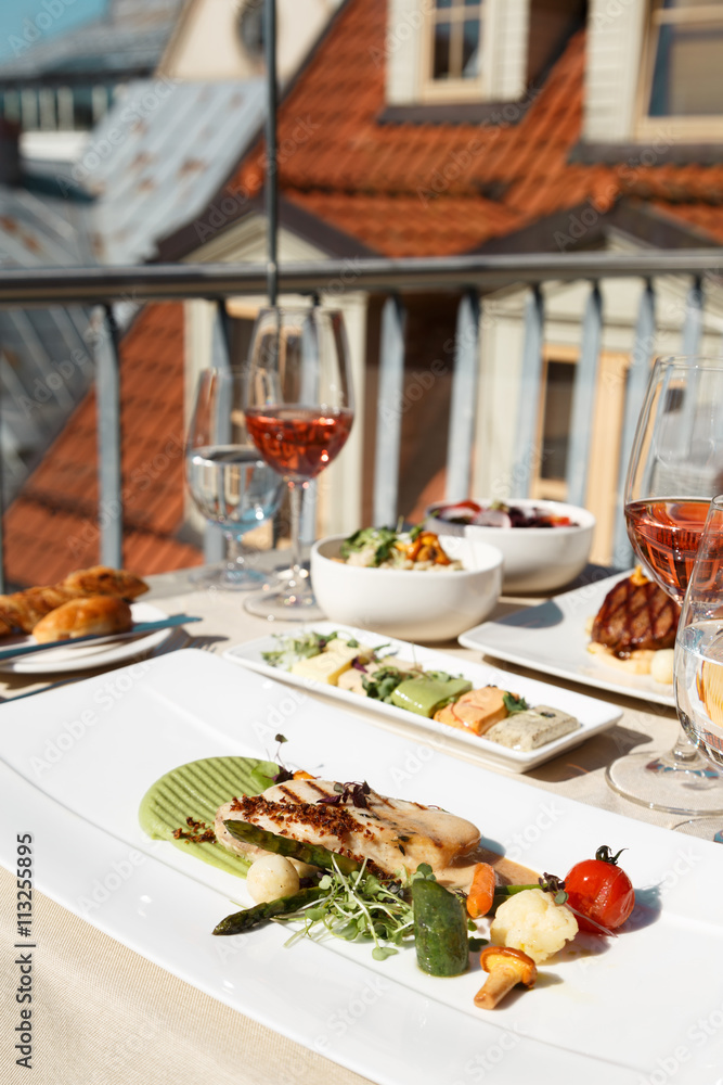 Table for two with food at rooftop restaurant, grilled fish garnish. Table for two with food at rooftop restaurant, grilled fish garnish.