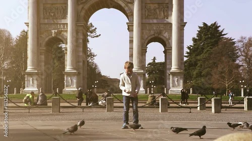 Fashionable boy feeds doves in Parco Sempione in Milan photo