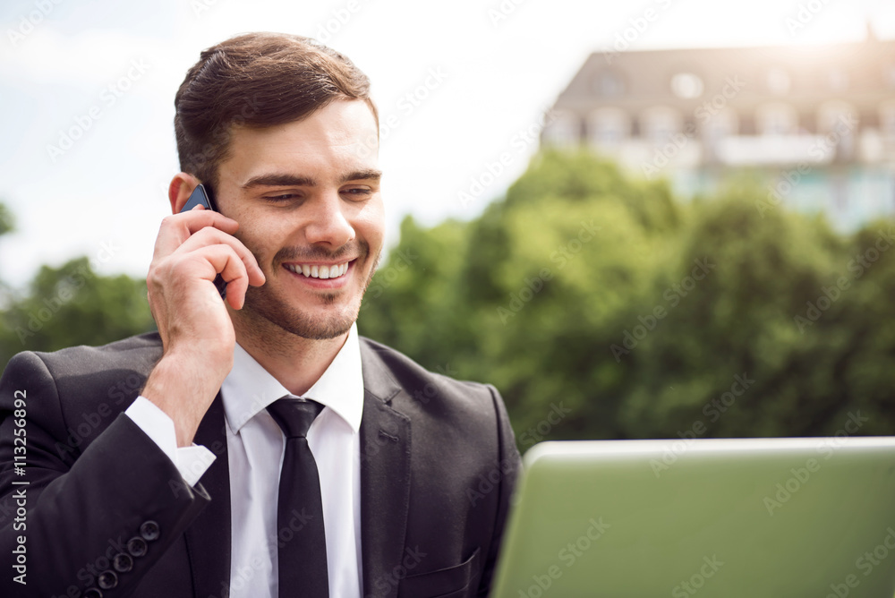 Handsome delighted man sitting on the grass