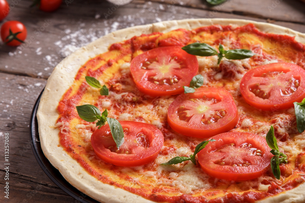 italian homemade pizza with sliced tomato topping
