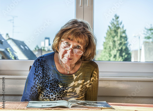 elderly attractive woman reading in a magazine photo