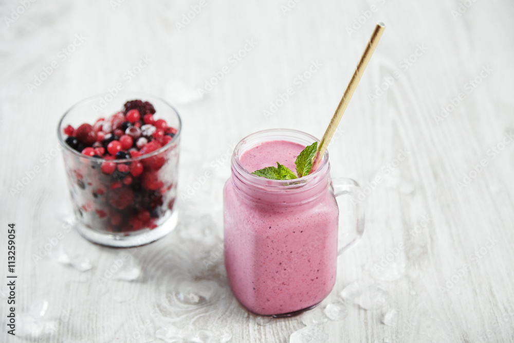 Transparent rustic jar with tasty healthly freshly made pale violet smoothie with drinking straw inside, near unfocused glass with frozen berries Melted ice around isolated on white table Transparent rustic jar with tasty healthly freshly made pale violet smoothie with drinking straw inside, near unfocused glass with frozen berries Melted ice around isolated on white table