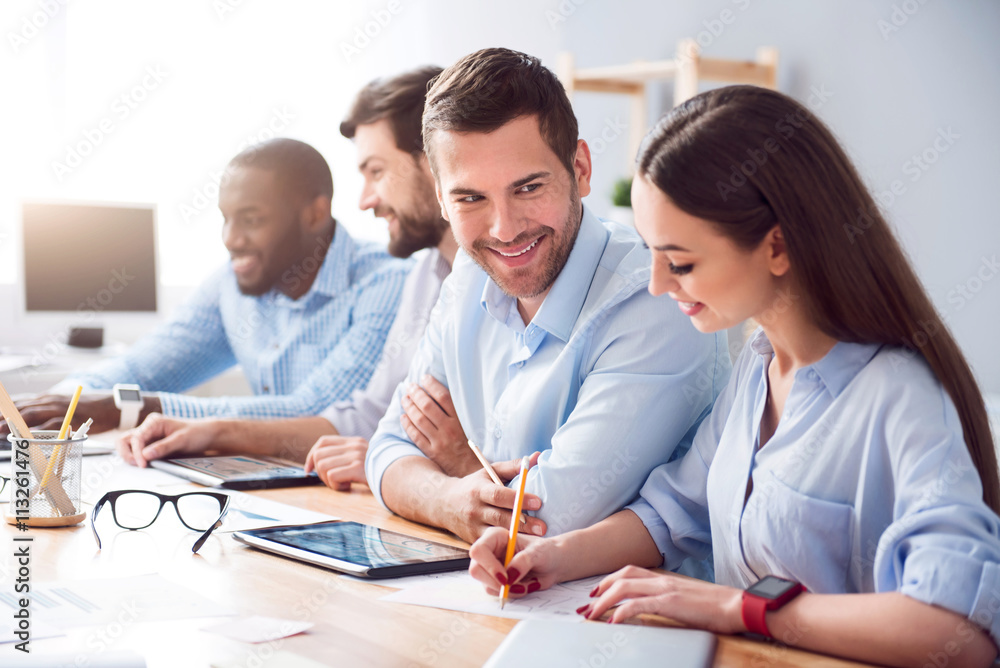Cheerful smiling colleagues sitting at the table Cheerful smiling colleagues sitting at the table