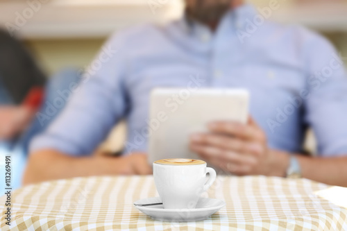 Cup of coffee and businessman on background