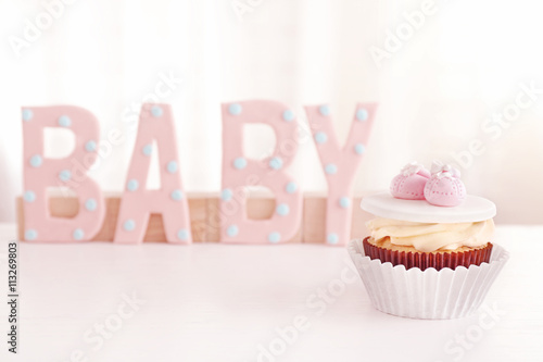 Word  Baby  with cupcake on light background