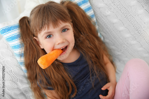 Little girl with carrot sit...