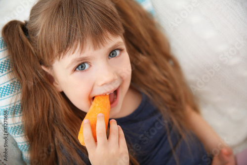 Little girl with carrot sit...