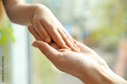Hands of mother and child on natural background