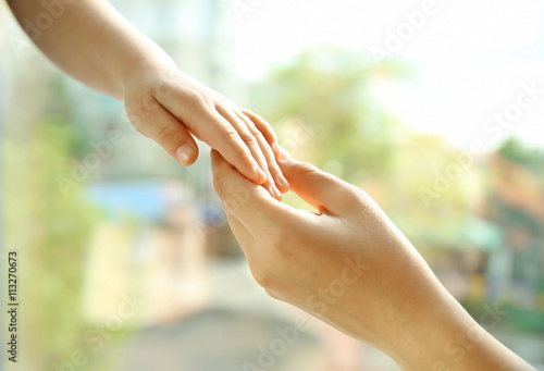 Hands of mother and child on natural background
