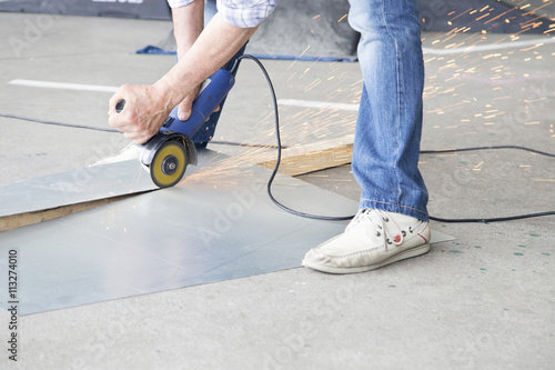 Worker grinding a metal plate in the street.