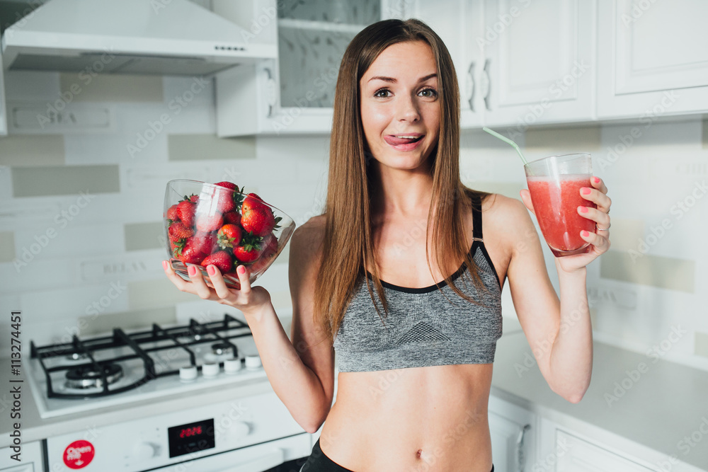 Sports and sexy girl drinks strawberry smoothie in the kitchen Sports and sexy girl drinks strawberry smoothie in the kitchen