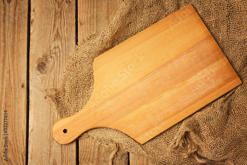 Cutting board on sackcloth on wooden table background. View from above
