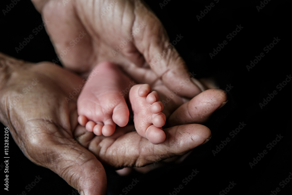 Baby feet cupped into grandmothers hands. (Soft focus and blurry Baby feet cupped into grandmothers hands. (Soft focus and blurry