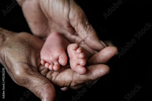 Baby feet cupped into grandmothers hands. (Soft focus and blurry