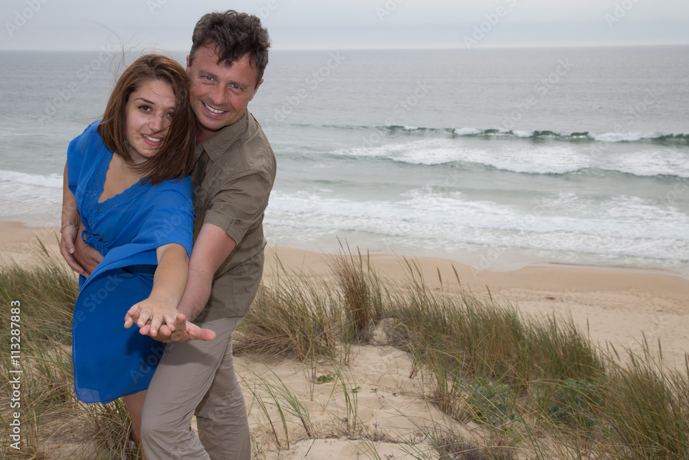 Smiling couple embracing on summer beach, having fun together,