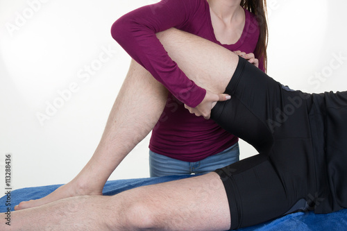 Real professional female masseur giving therapeutic massage to man's legs