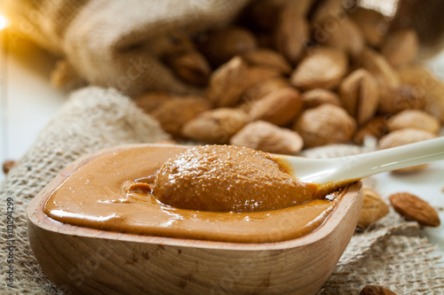Homemade almond butter in a wooden bowl and a bag of jute.