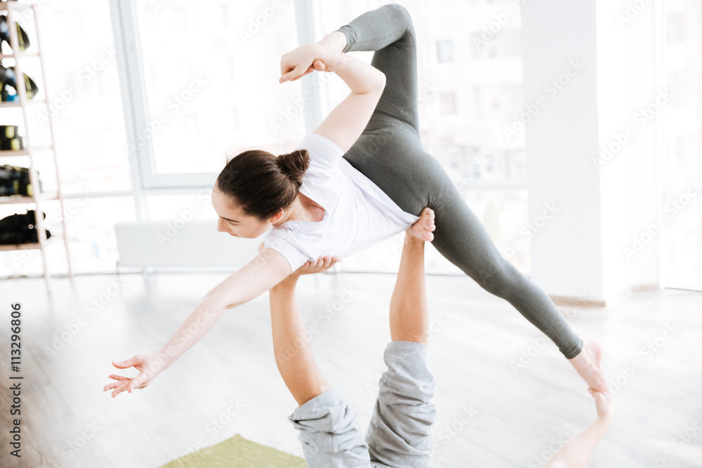 Woman balancing on male feet while doing acro yoga Woman balancing on male feet while doing acro yoga