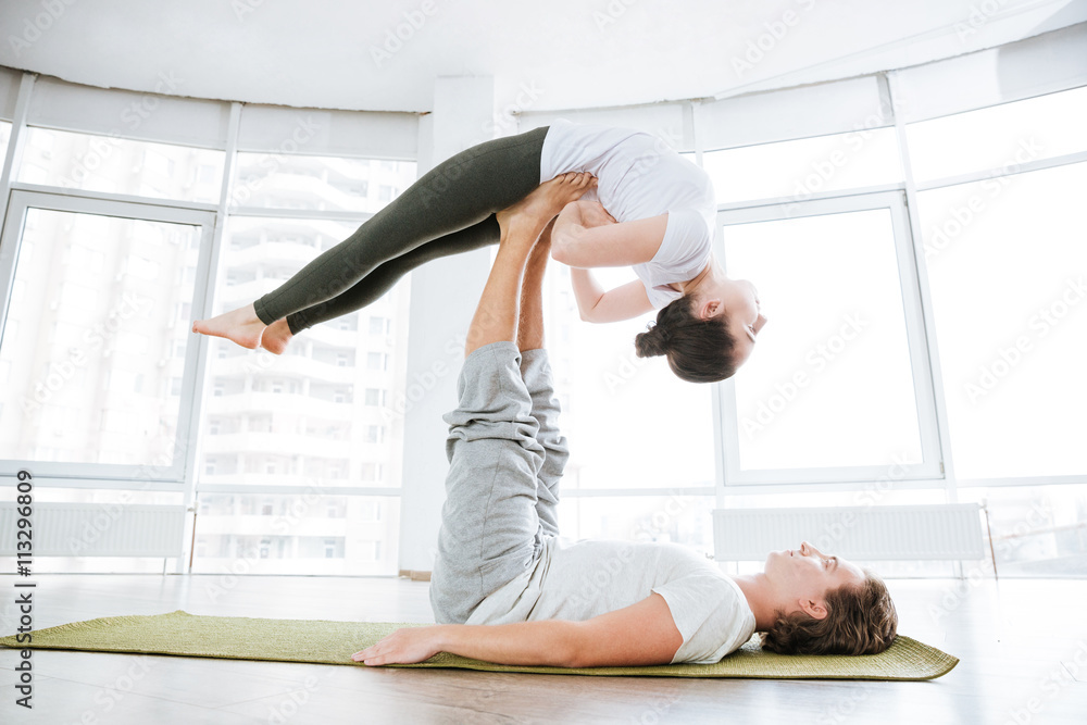 Peaceful woman practicing acro yoga with partner