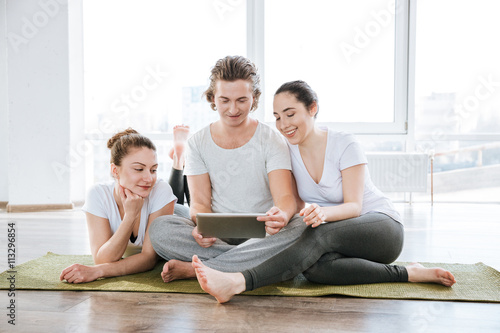 Man and two women using tablet in yoga studio together