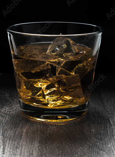 Glass of whiskey and ice on a wooden table