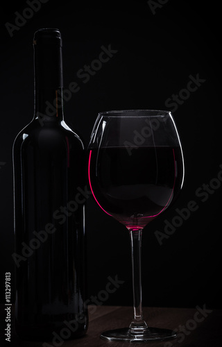 Elegant red wine glass and a wine bottle