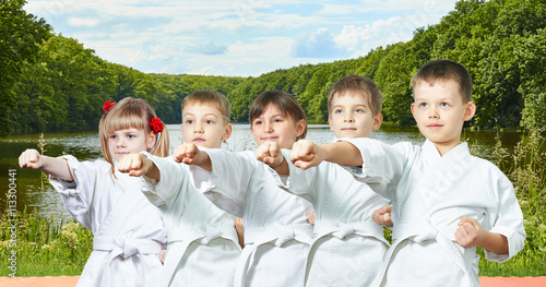 Young children are hitting a punch arm on the background of nature and water