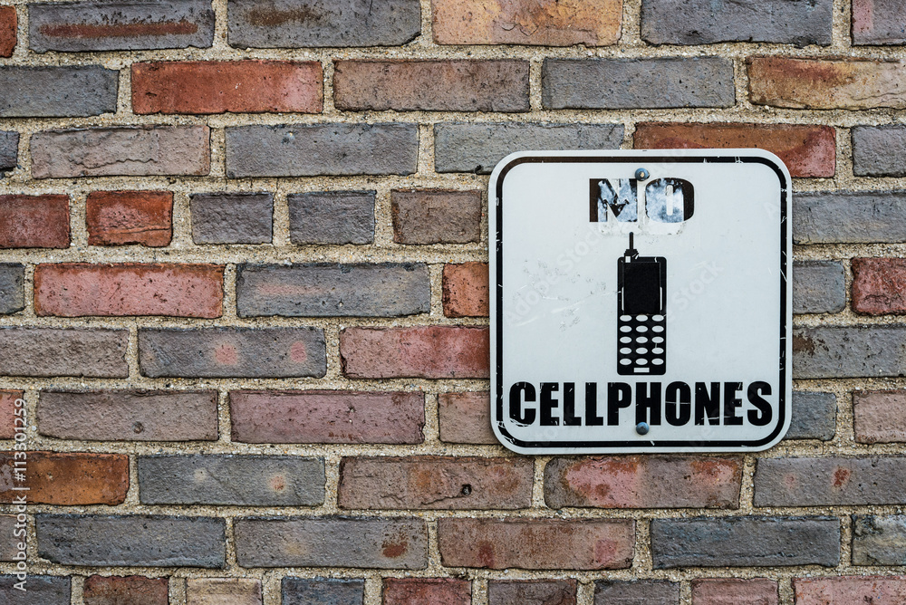 no cell phones warning sign on brick wall background no cell phones warning sign on brick wall background