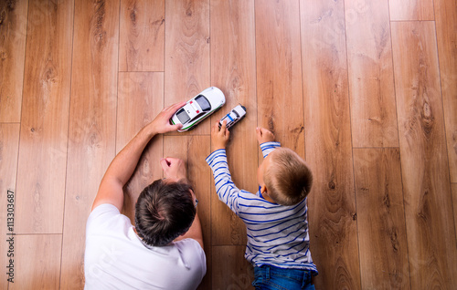 Unrecognizable father with his son playing with cars