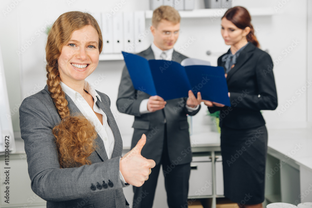 business woman working in office shows thumb up