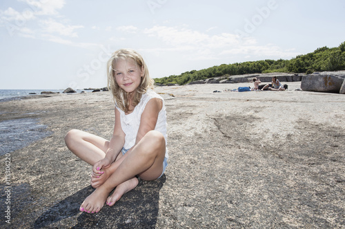 Portrait of smiling girl sitting on shore photo