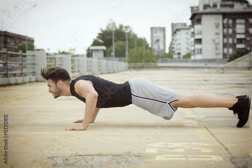 Muscular man doing push ups outdoors