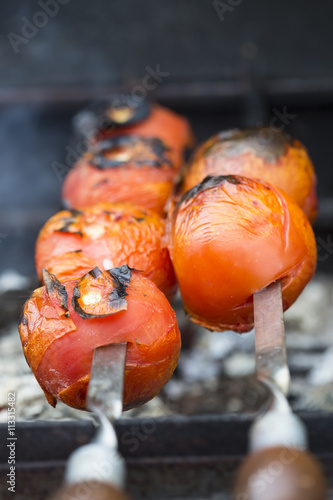 Grilled tomatoes on skewer with juice and fire