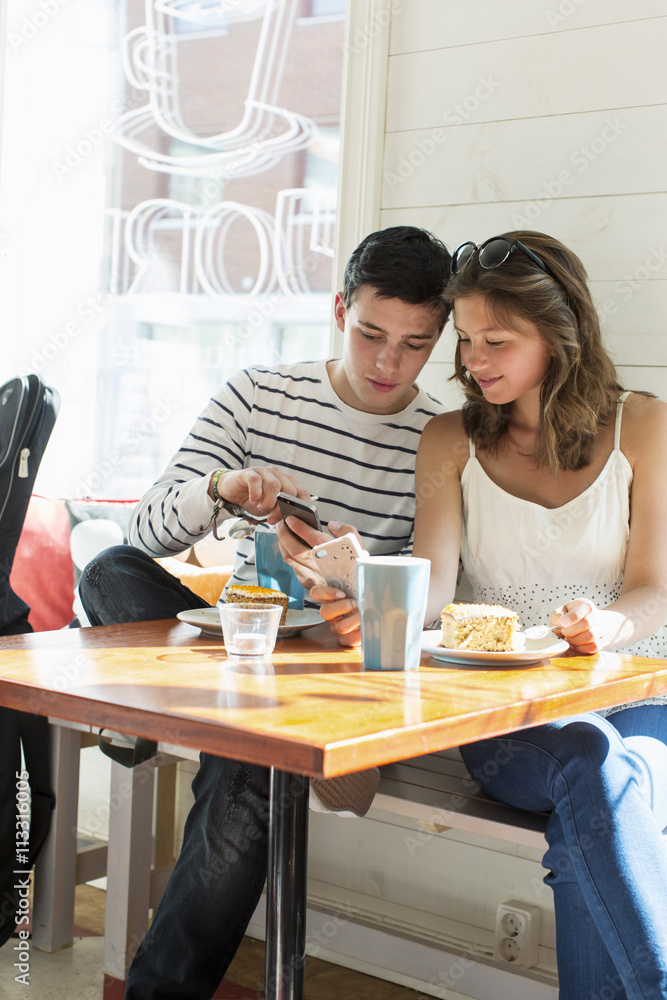 Couple using mobile phones while sitting at restaurant table Couple using mobile phones while sitting at restaurant table