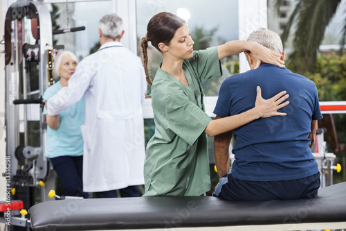 Physiotherapist Massaging Senior Man's Back