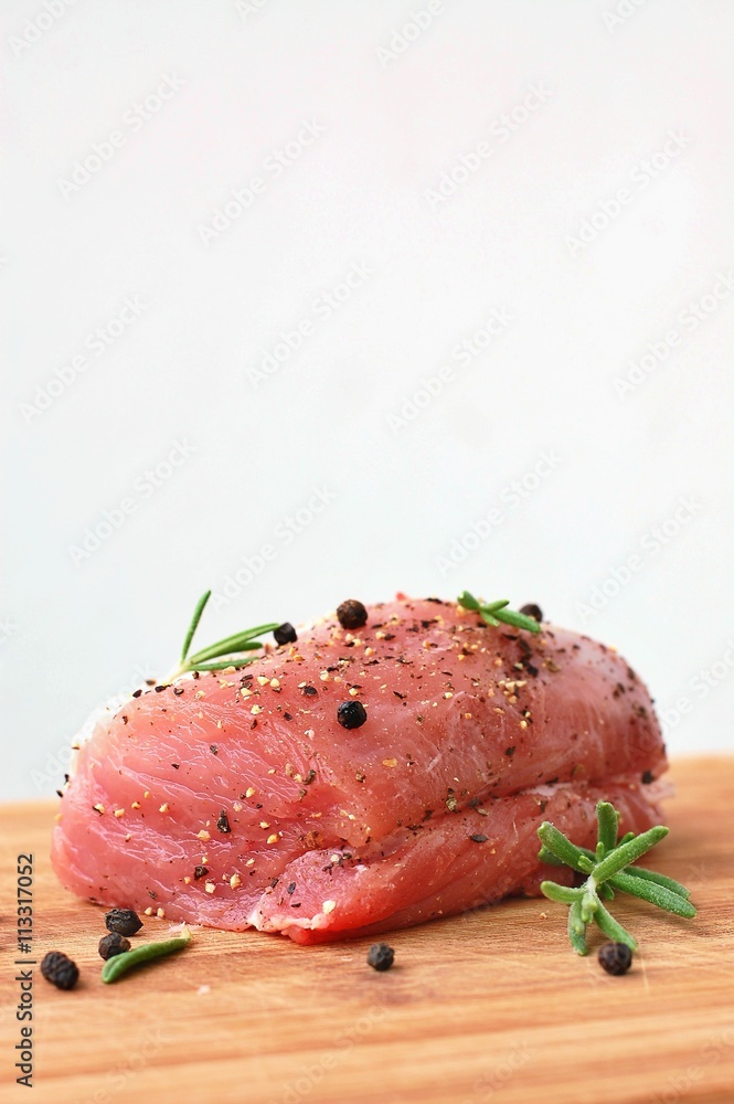 Raw pork meat tenderloin with black pepper and rosemary on wood prepared to cook Raw pork meat tenderloin with black pepper and rosemary on wood prepared to cook