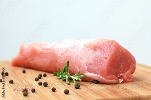 Raw pork meat tenderloin with black pepper and rosemary on wood prepared to cook