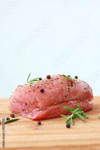 Raw pork meat tenderloin with black pepper and rosemary on wood prepared to cook