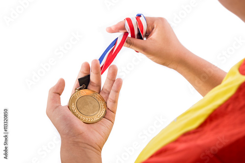 Athlete holding gold medal with ribbon on his hand